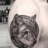 Circle shaped black ink upper arm tattoo of cute wolf portrait