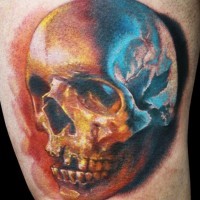 Tatuaje en el brazo, cráneo de colores amarillo y azul