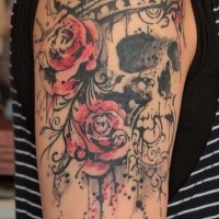 Tatuaje en el brazo, cráneo con plumas en la cabeza, rosas