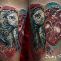 Colored biceps tattoo of owl with human heart