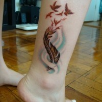 colorato tatuaggio con piume e branco di uccelli su gamba
