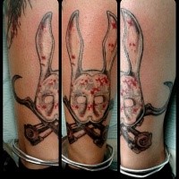 Colored funny looking leg tattoo of bunny like mask with crutches