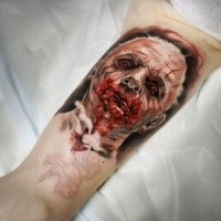 Colored horror style creepy looking biceps tattoo of bloody man face
