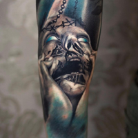 Colored horror style forearm tattoo of creepy monster face