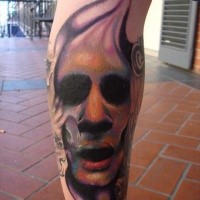 Colored horror style terrifying face tattoo on leg muscle