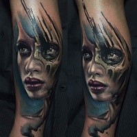 Colored realism style forearm tattoo of woman with skull