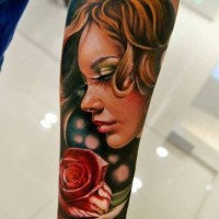 Tattoo von farbigem Porträt einer jungen Frau mit Rose am Unterarm