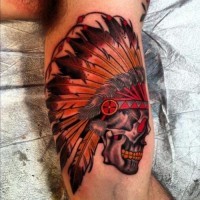 Bunter Schädel in einem indianischen Kopfschmuck Tattoo am Arm