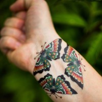 Tatuaggio colorato sul polso tre farfalle formano il triangolo