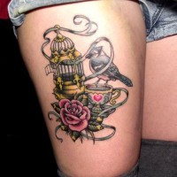 Coloured cage with bird and a cup of tea tattoo on thigh