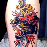 pugnale colorato trafigge testa di pantera nera tatuaggio sulla gamba