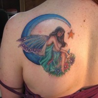 Coloured fairy sitting on moon tattoo on shoulder blade