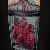 Coloured heart in a bird cage tattoo