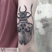 Tatuaje en el antebrazo,
escarabajo gris con silueta de cráneo