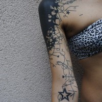 Tatuaje en el brazo, mancha grande con estrellas y corazones diminutas, tinta negra