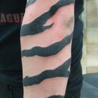 Tatuaje en el brazo, emblema de AC/DC y rayas negras de tigre