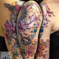 Tatuaje colorido en el hombro,
rama con flores lindas y nido con huevos