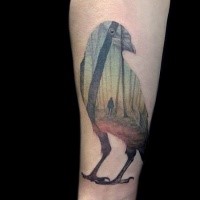 Cool looking colored forearm tattoo of crow with human in forest