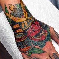 Tatuaje colorido en la mano, 
casco sonriente de samurái