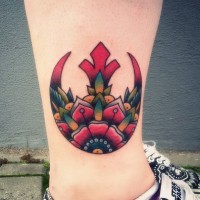 Tatuaje en el tobillo, 
 emblema de la alianza Rebelde rojo estilizado con flor extraña
