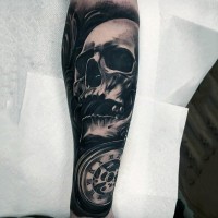 Cool vintage style black ink skull tattoo on forearm with old mechanic clock