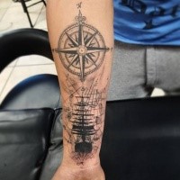 Creative black ink forearm tattoo of sailing ship with compass