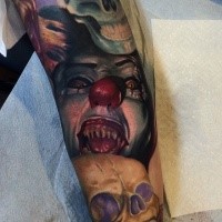 Creepy colored horror style big arm tattoo of demonic clown and skull