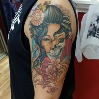 Tatuaje multicolor en el hombro,
mitad geisha mitad cráneo aterrador