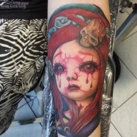 Creepy horror like colored crying with bloody tears doll tattoo on forearm