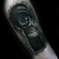 Tatuaggio dall'occhio inquietante in bianco e nero dell'occhio che guarda attraverso il buco della serratura