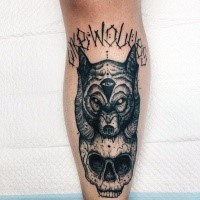 Creepy looking black ink leg tattoo of creepy skull with wolf head and lettering