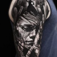 Creepy looking black ink shoulder tattoo of man monster face