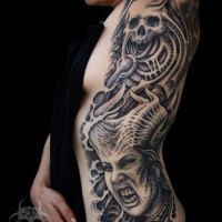 Creepy looking black ink side and arm tattoo of demonic woman with skull