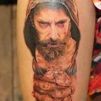 Creepy looking colored thigh tattoo of man with hood and cross