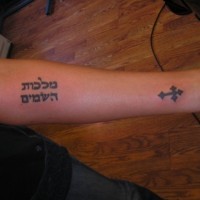Tatuaje en el antebrazo,
 frase hebrea y cruz