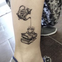 Tatuaje en la pierna, libros con taza de té y tetera, colores negro blanco