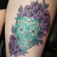 Tatuaje en la pierna, cráneo verde decorado con flores