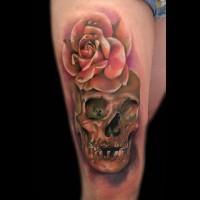 Nett gemalter und farbiger Schädel Tattoo am Oberschenkel mit detaillierter Rose Blume