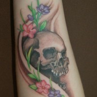 Tattoo von Totenkopf mit süßen Blumen am Unterarm