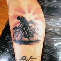 Radfahrer fährt auf dem Fahrrad  in der dämrigen Berge Tattoo mit Schriftzug