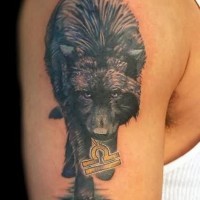 Dark a wolf with a sign in mouth tattoo on shoulder