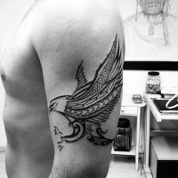 Dark black and white flying eagle tattoo on shoulder in tribal style