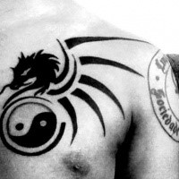 Dark black ink Asian Yin Yang symbol and winged stylized dragon chest tattoo