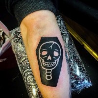 Dark black ink coffin with white funny skull tattoo