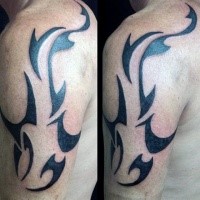 Dark black ink cool swimming shark tattoo on shoulder in tribal style