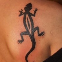 Dark black ink crawling lizard stylized tattoo on shoulder blade