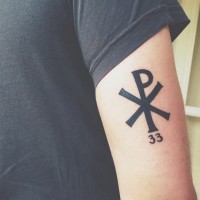 Tatuaje en el brazo,  Crismón  símbolo Chi Rho y numero 33, tinta negra