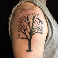 Dark black ink tree with several leaves and roots shoulder tattoo with black crow
