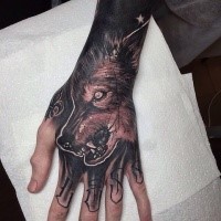 Dark colored black and gray style creepy wolf head tattoo on hand