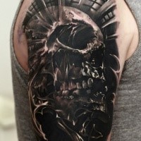 Dark realistic looking shoulder tattoo of human skull with ornaments